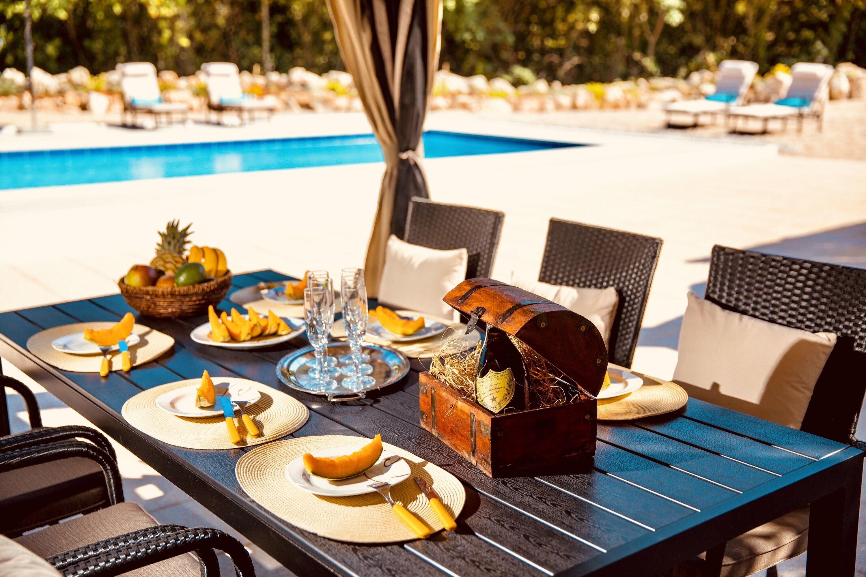 An outdoor dining area with a pool in the background.