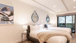 A modern bedroom with two beds, a large window, and a painting of a mountain landscape. - Villa Cortina Condo with 5 Minutes Walk to Gondola by RedAwning (Vail)