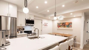 A modern kitchen with stainless steel appliances, a central island with seating, and recessed ceiling lighting. - Villa Cortina Condo with 5 Minutes Walk to Gondola by RedAwning (Vail)