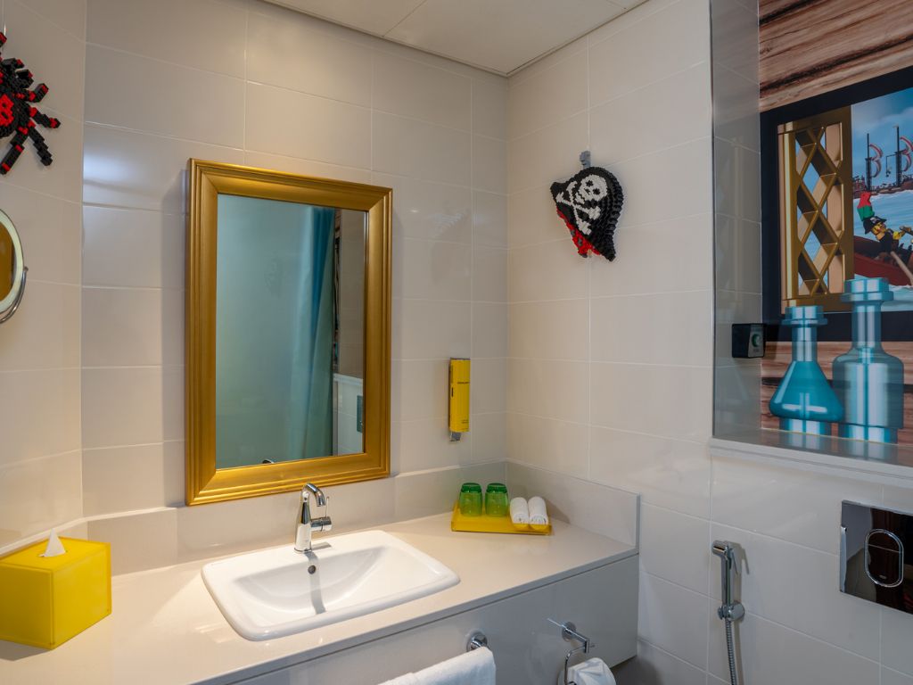 A modern bathroom with a large mirror, a sink, and a shower.
