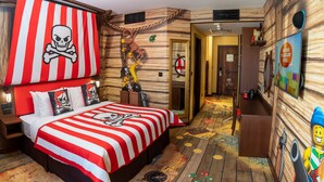 Une chambre sur le thème des pirates, avec un lit, un mur en bois, une porte et un panneau fixé au mur.