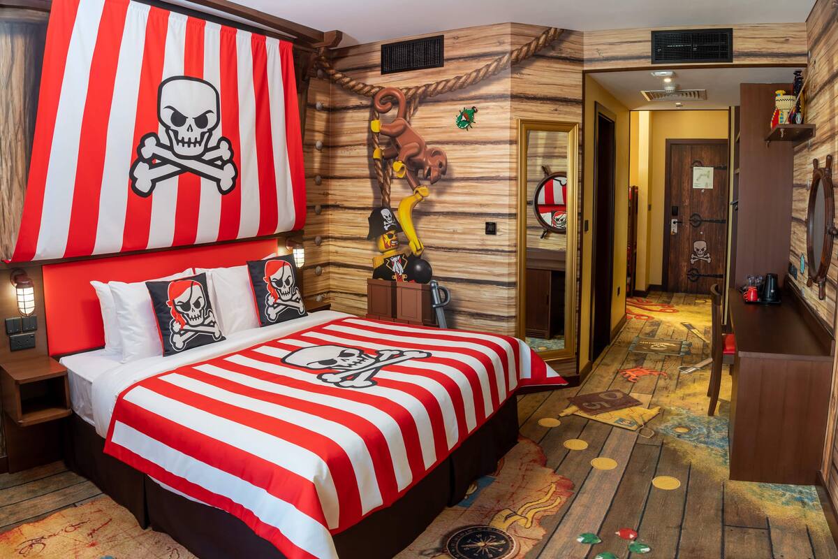 Habitación temática de piratas con cama, pared de madera, puerta y letrero en la pared.