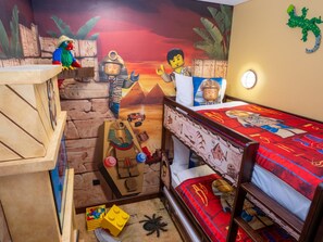 Habitación infantil con un mural al estilo desierto, una cama litera y juguetes LEGO.