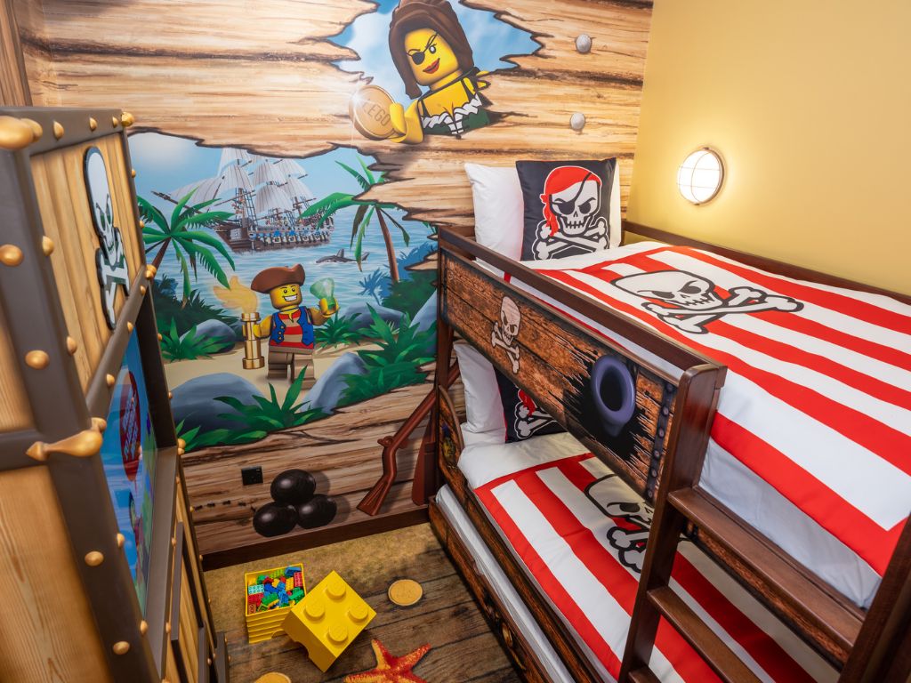 A child's bedroom with a pirate-themed mural, a bunk bed, and a LEGO play area.