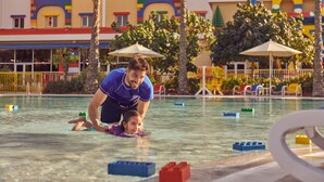 A swimming pool area with a person assisting a child. - LEGOLAND Hotel Dubai (Dubai)