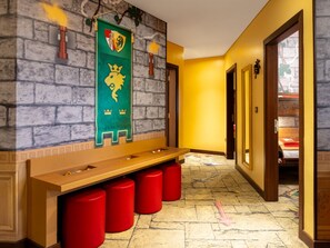 Un pasillo con un banco, taburetes rojos y una pared con un escudo.