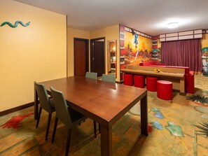 A dining area with a wooden table and chairs, a red bench, and a colorful mural on the wall. - LEGOLAND Hotel Dubai (Dubai)