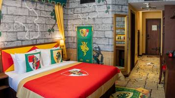 Quarto de hotel com parede de tijolos, cama com colcha vermelha e faixa verde e dourada.