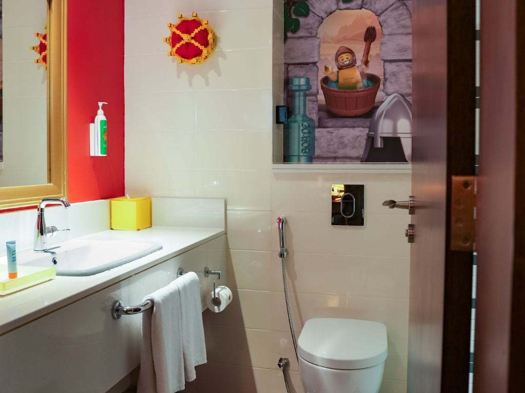A bathroom with a white sink, a mirror, a toilet, and a shower area.