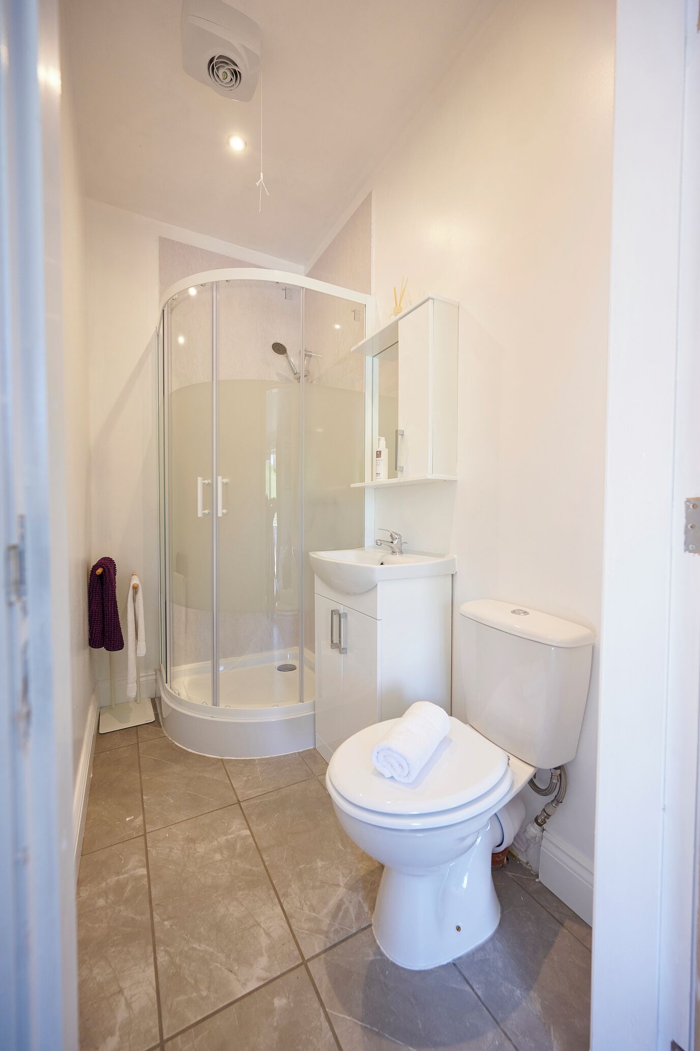 A modern bathroom with a glass-enclosed shower, a white toilet, and a sink.