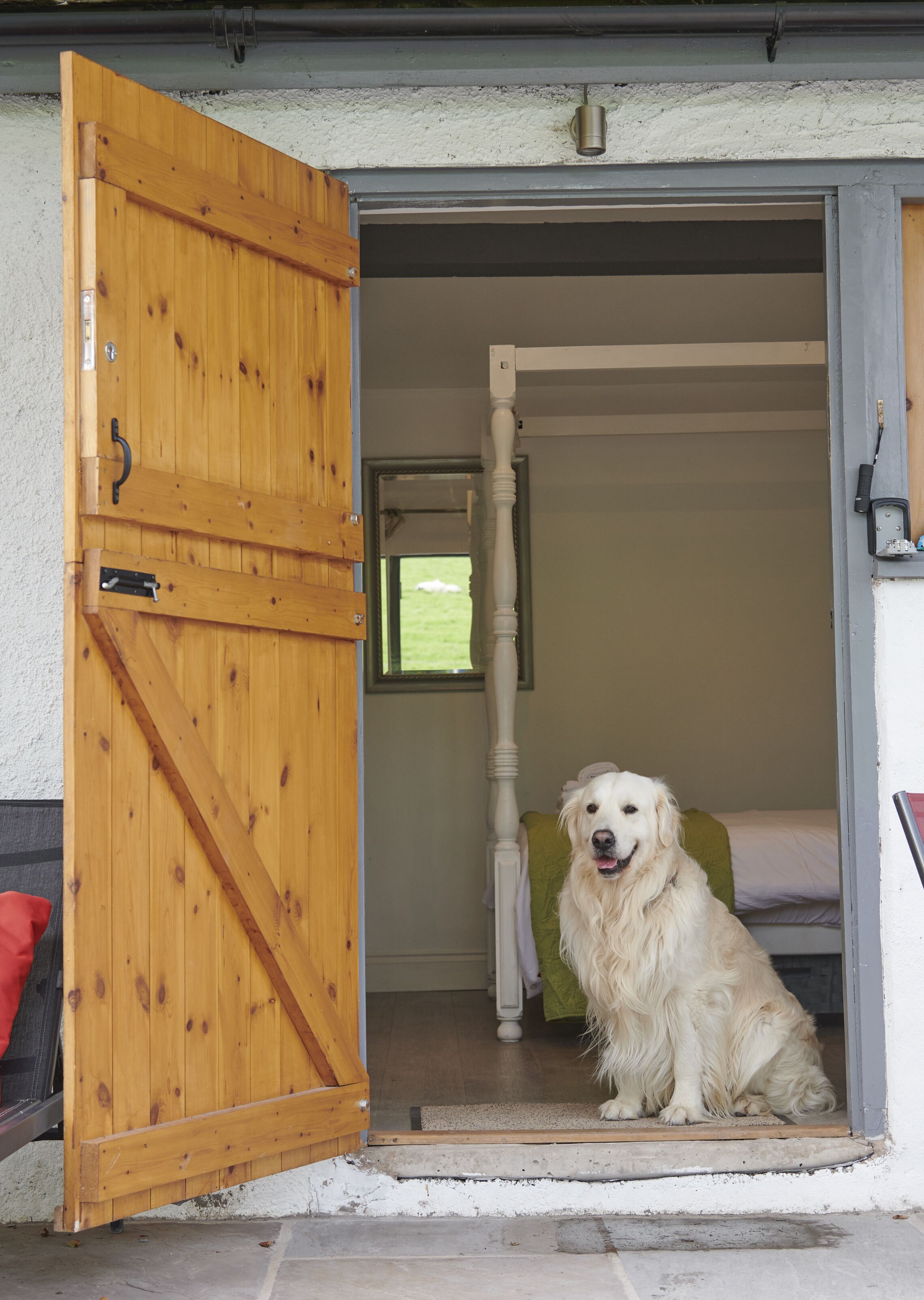 Een houten deur die leidt naar een kamer met een bed en een raam.