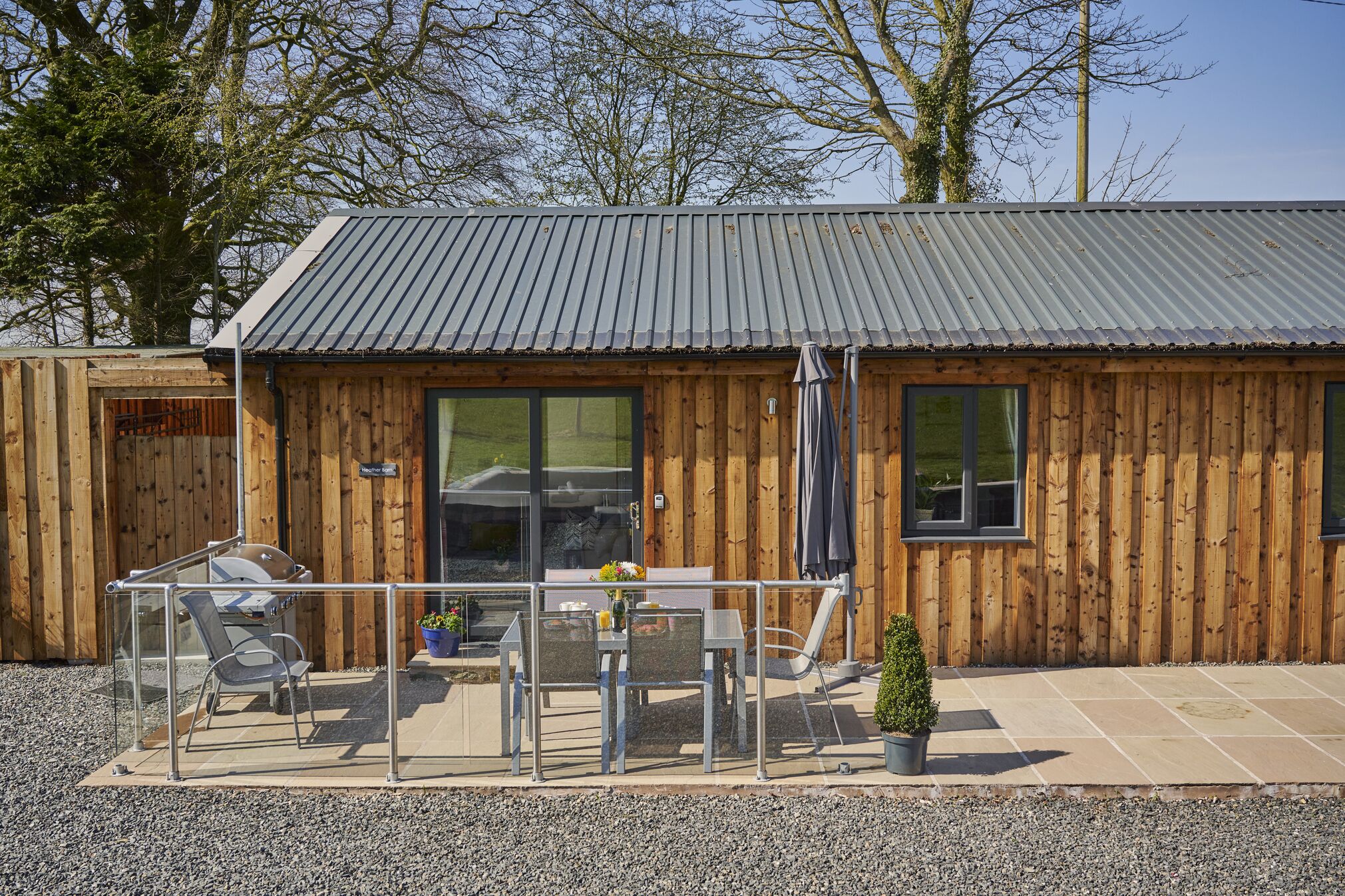 Eine Holzhütte mit Metalldach, einer Terrasse mit Tisch und Stühlen und einem kleinen Topfpflanze.