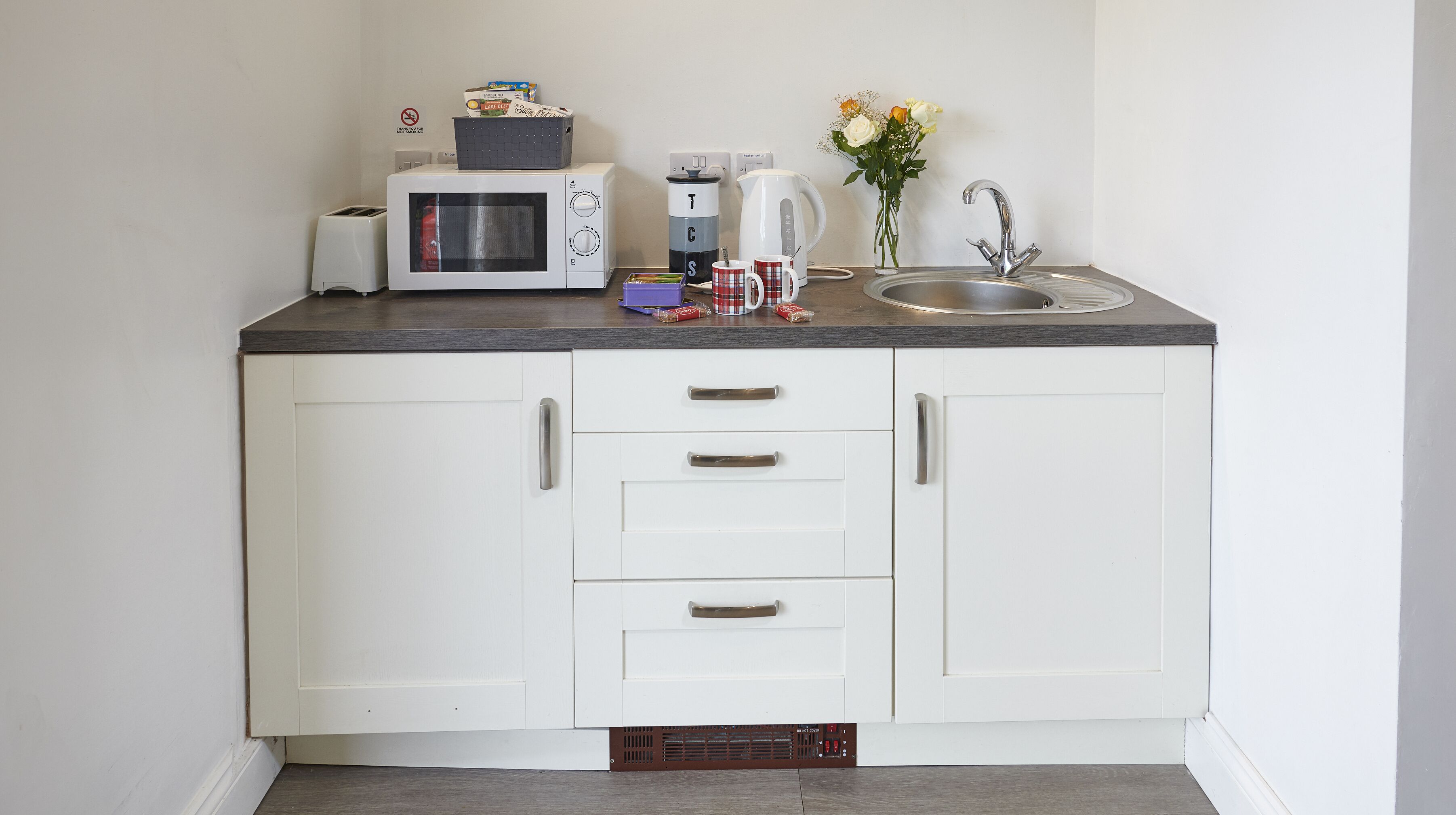 A compact kitchen with a microwave, coffee maker, and sink.