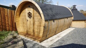 A wooden, arched, single-room structure with a dark shingled roof, a hexagonal window, and a door. - Newlands Farm Stables (Kendal)