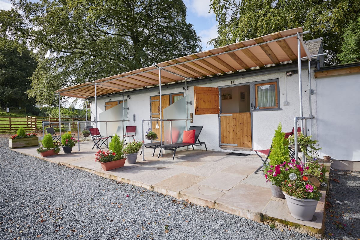 A building with a covered patio area, outdoor seating, and potted plants.