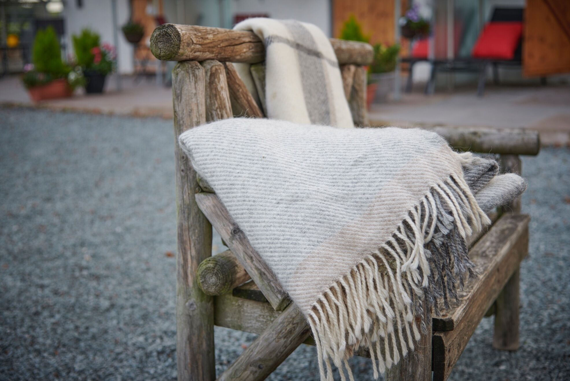 Una silla de madera rústica con un chal tejido blanco y flecos.