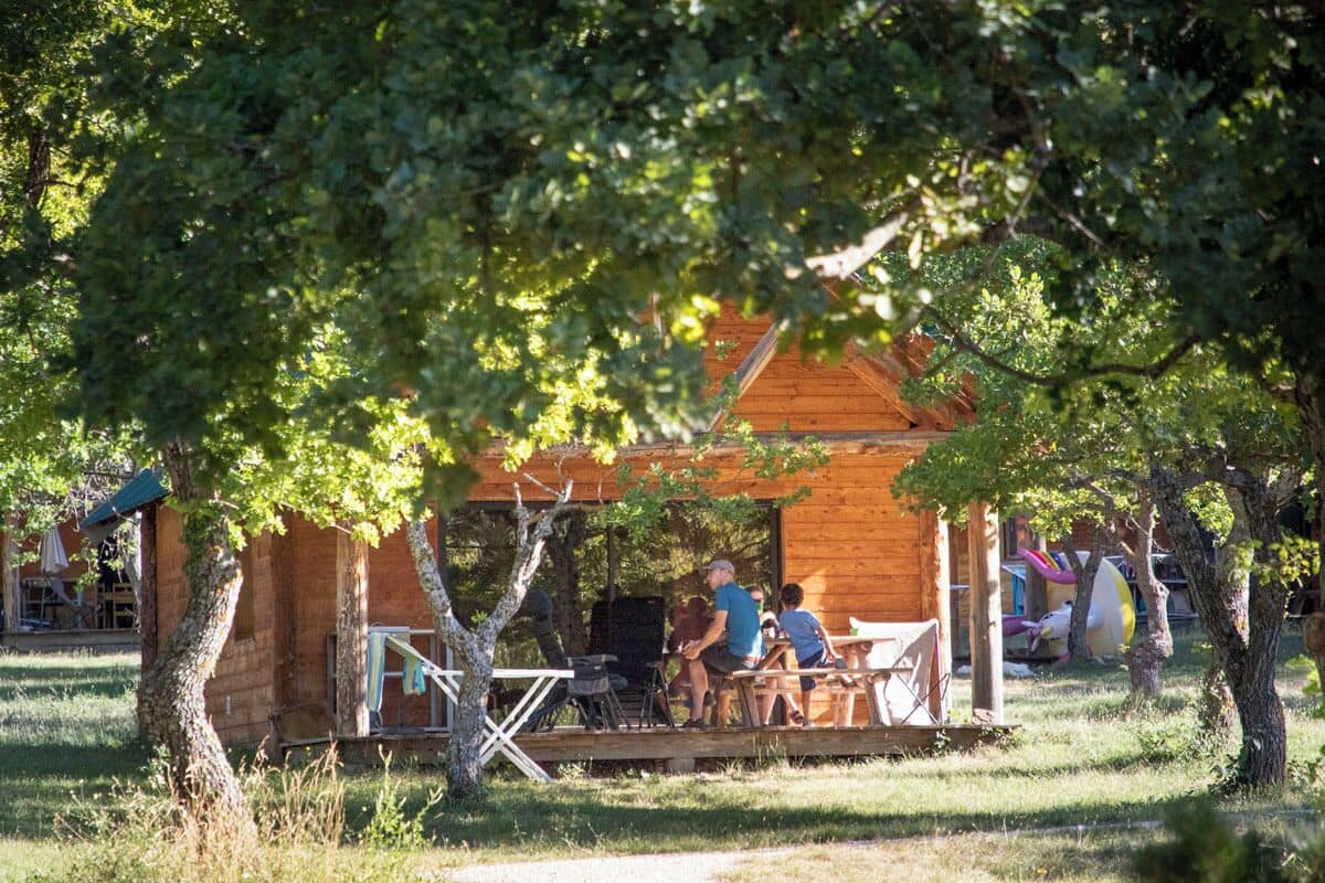 Un chalet en bois rustique doté d’une terrasse, entouré d’arbres.