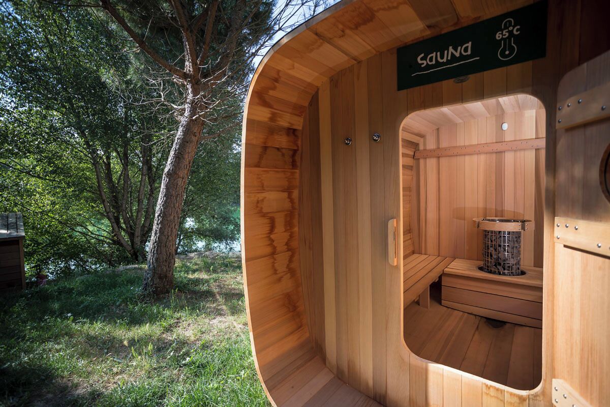 Una sauna con interior de madera, un banco y un calentador.