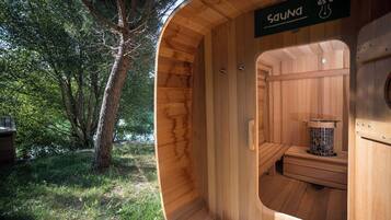 Una sauna con interior de madera, un banco y un calentador.