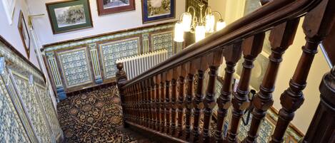 Una imponente escalera con barandales ornamentados y alfombra estampada.