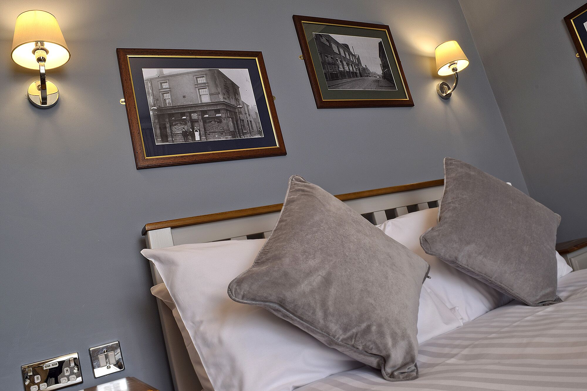 Une chambre d’hôtel avec un lit, deux oreillers et deux cadres photo fixés au mur.