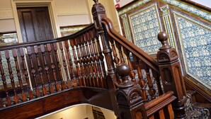 A wooden staircase with ornate balusters and a handrail, leading to a door with a number '4' sign.