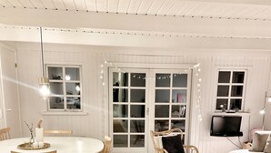Un salon chaleureux avec une table de salle à manger ronde, des chaises en bois, un canapé et un téléviseur.
