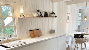 Une cuisine moderne avec des meubles blancs, un îlot central en bois et un coin repas comprenant une table et des chaises.