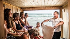Un groupe de personnes se trouve dans une cabane en bois, d’où l’on a une vue sur l’océan.