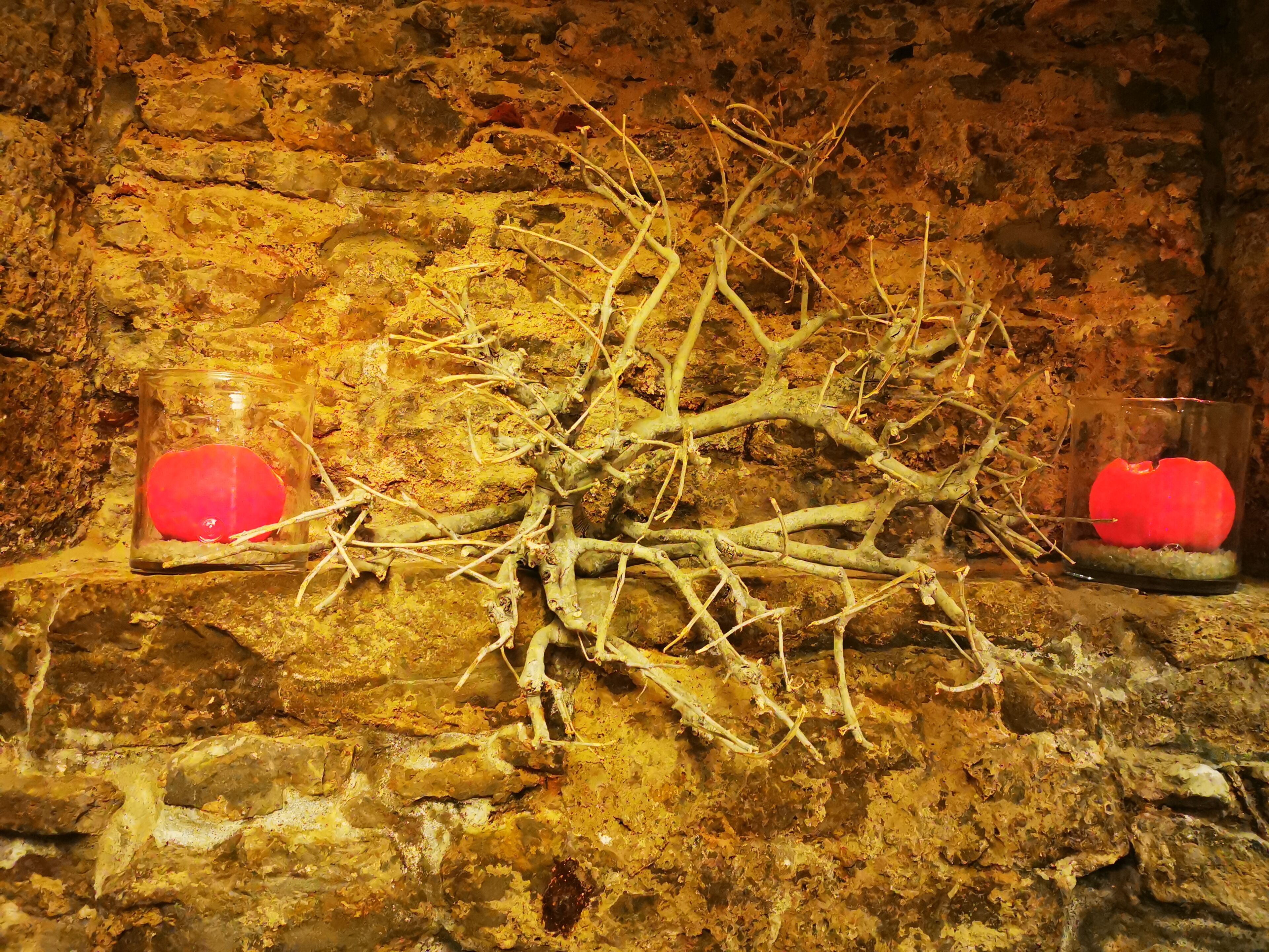 A stone wall with two glass candle holders containing red candles.