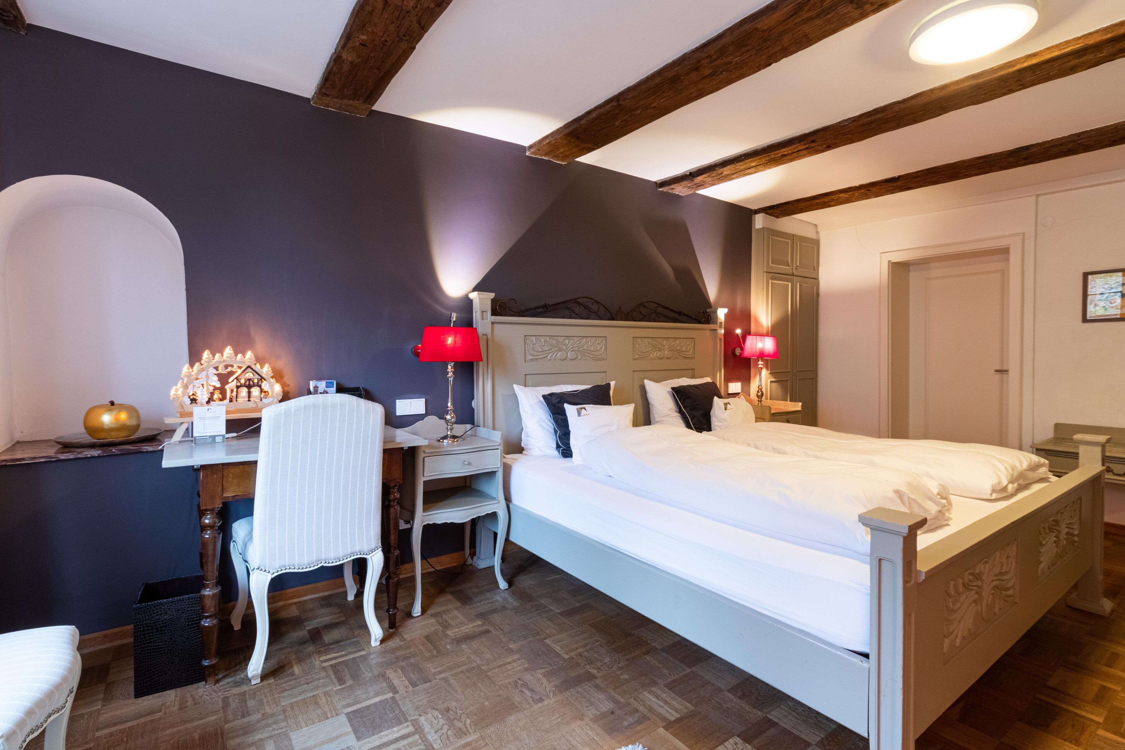 Une chambre à coucher comprenant un lit, un bureau, une chaise et deux lampes de chevet.