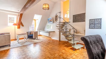 Ein geräumiges Loft mit Holzboden, einer modernen Treppe und einer gemütlichen Sitzecke.