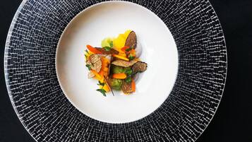 Un plato blanco con un diseño tipo mosaico, sobre una superficie negra.