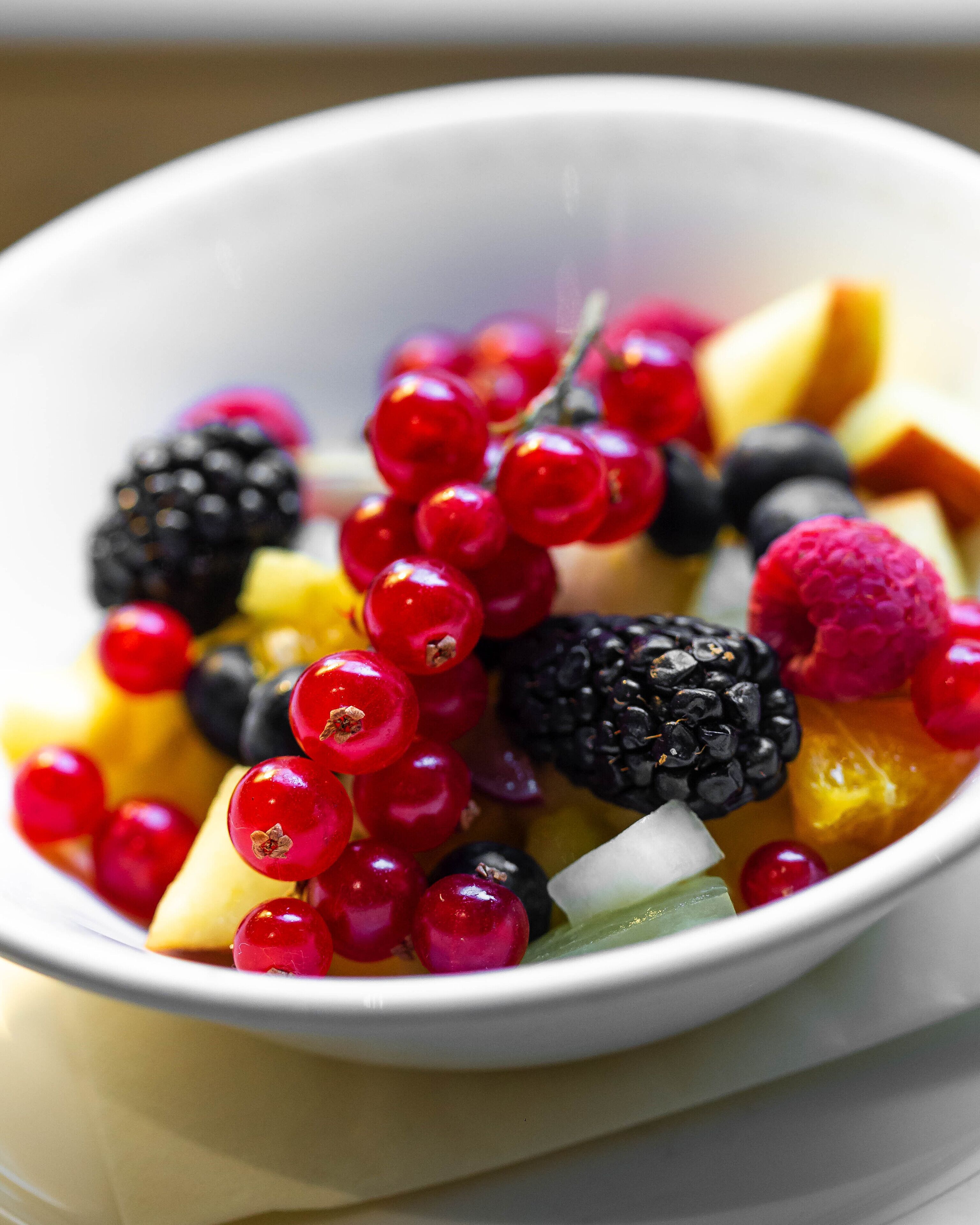 A bowl of mixed fruit salad with berries and melon.