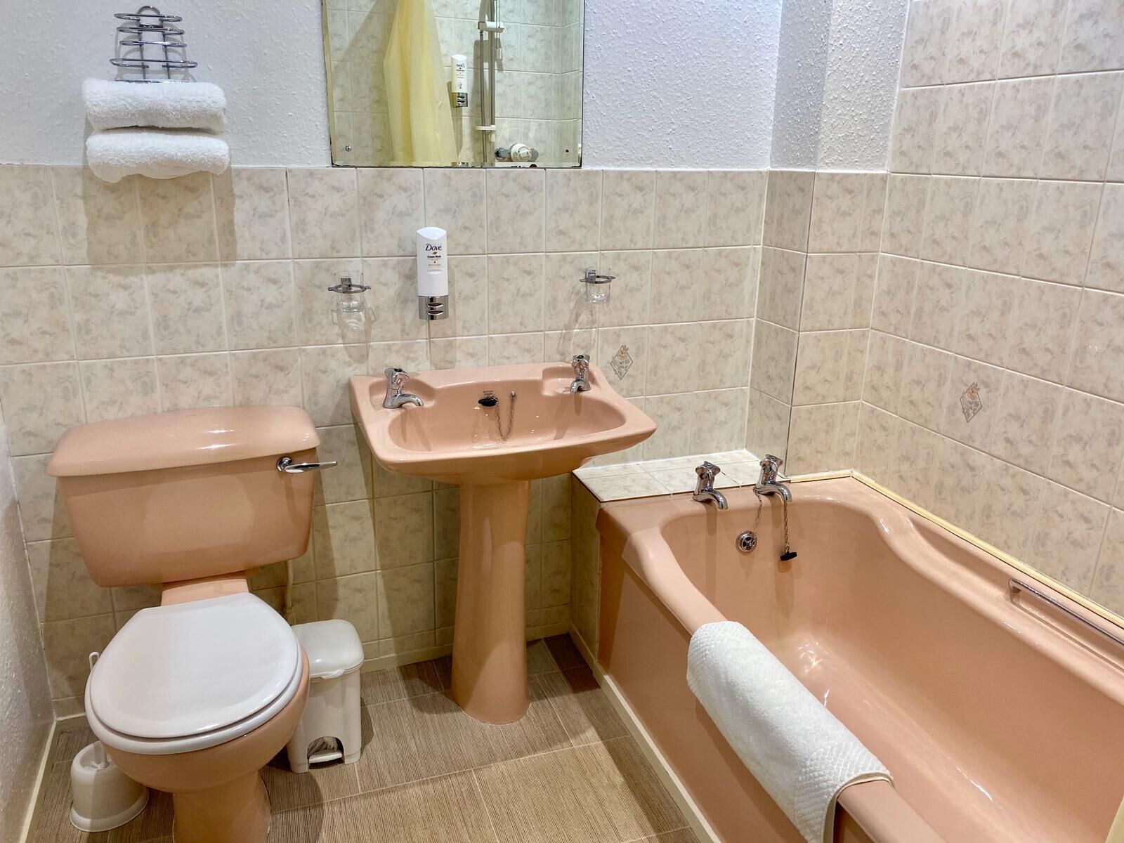 Ein Badezimmer mit Toilette, Waschbecken und Badewanne, alle in einem passenden pinkfarbenen Farbkonzept.