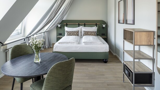 Ein modernes Schlafzimmer mit einem Bett, einem runden Tisch mit Stühlen, einer Blumenvase und einer eingebauten Regaleinheit.