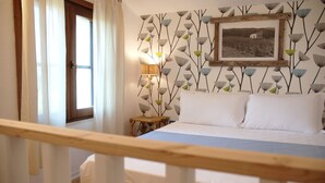A bedroom with a bed, a nightstand, a lamp, and a window with curtains. - Hotel Galman (Carloforte)