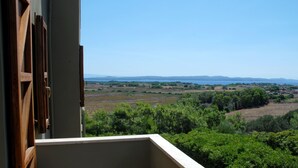 A balcony with a view of a coastal landscape, including fields and distant mountains. - Hotel Galman (Carloforte)
