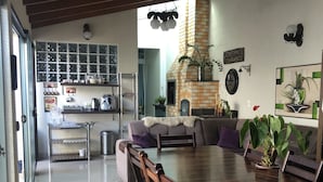 A modern kitchen with a brick oven, a dining area with a long wooden table and chairs, and a living area with a sofa and a coffee table. - Pousada da Paz (Curitiba)