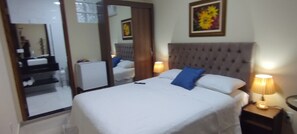 A hotel room with a large bed, two bedside lamps, a mirror, and a framed floral artwork on the wall. - Pousada da Paz (Curitiba)