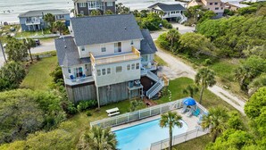 A large two-story house with a swimming pool, surrounded by lush greenery and a view of the ocean. - Private Pool, Ocean View, Beach Access Across Street - Castle By The Sea (Folly Beach)