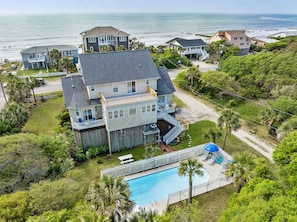 A large two-story house with a swimming pool, surrounded by lush greenery and a view of the ocean. - Private Pool, Ocean View, Beach Access Across Street - Castle By The Sea (Folly Beach)