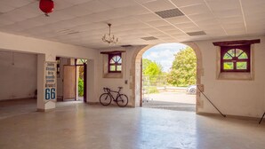 Una habitación amplia con una bicicleta, un letrero que indica un centro Renault 66, y una vista a través de un arco hacia el exterior.