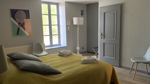 Un dormitorio con cama, una silla, una ventana y una puerta.