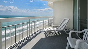 A balcony with white chairs, a glass door, and a view of the ocean. - Water's Edge 1511 - Two Bedroom, Two Bathroom, Oceanfront Condo (Garden City Beach)
