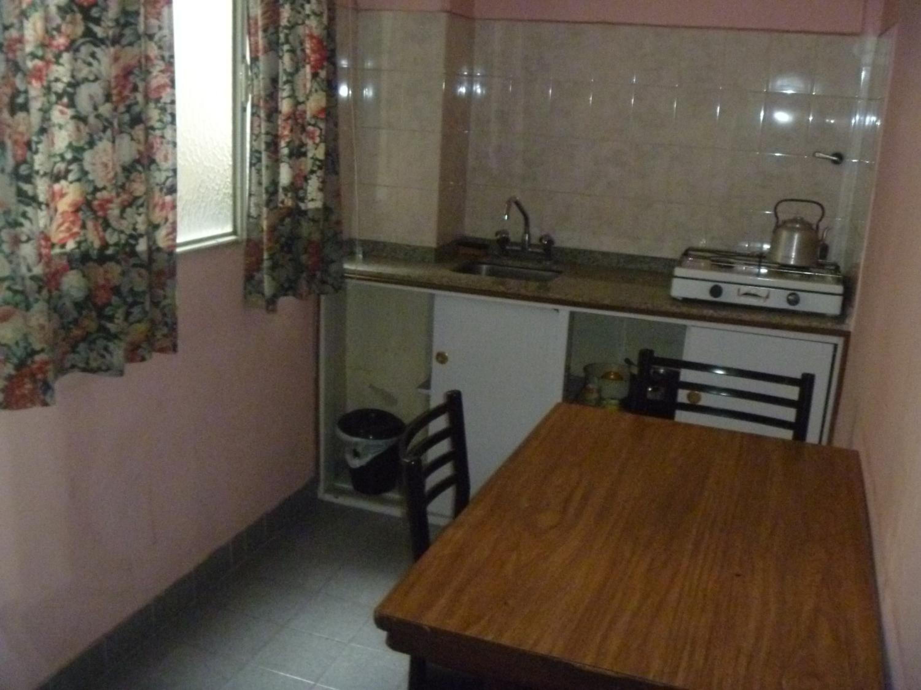 Cocina pequeña con estufa, lavamanos y un mueble.