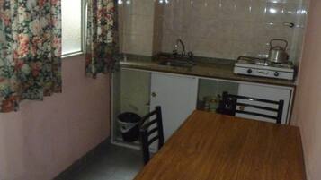 Cocina pequeña con estufa, lavamanos y un mueble.
