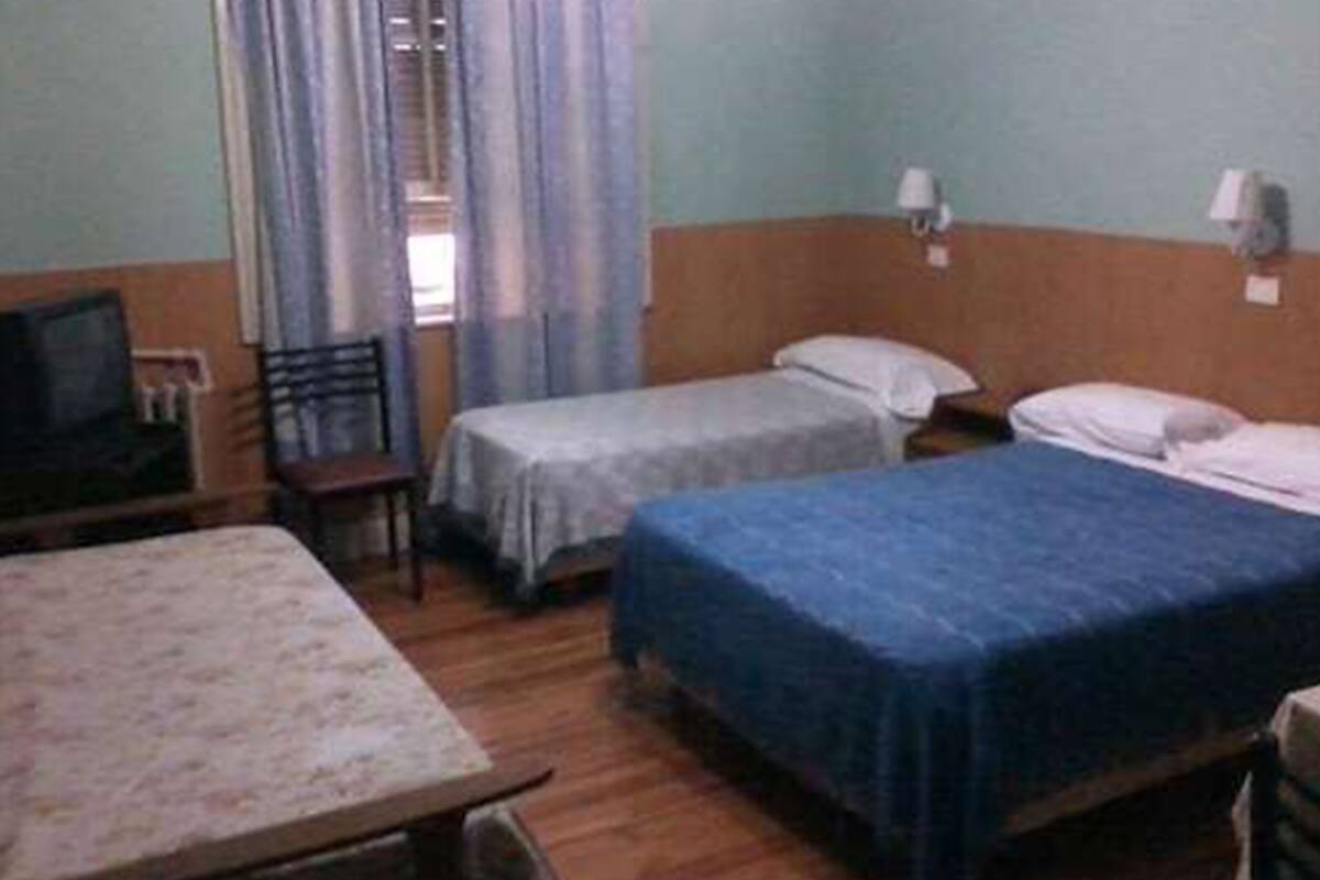 A room with two single beds, a wooden table, a chair, and a television.