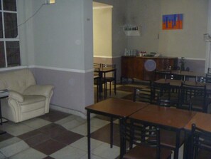 Une pièce avec un sol à carreaux, un canapé, une table à manger avec des chaises et un buffet.