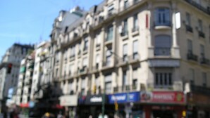 A multi-story building with a classic architectural style, featuring a ground-floor commercial space with various shops and a visible restaurant sign. - Hotel San Martin (Buenos Aires)